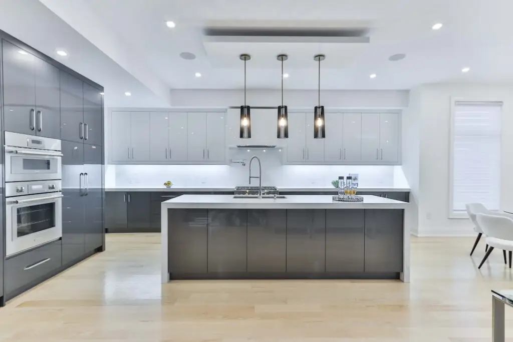 Modern kitchen with grey and white cabinetry, stainless steel appliances, and a central island.